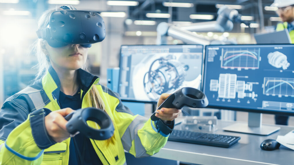 Female worker with VR gear and hand controller in front of computer